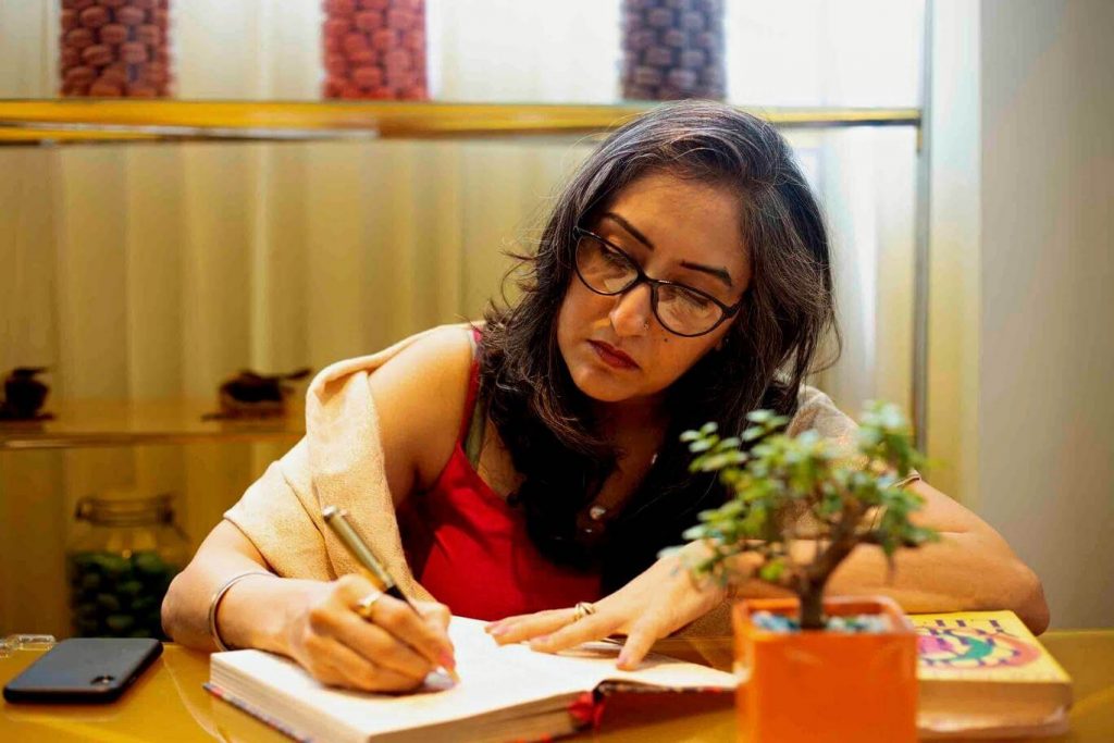 A Woman wearing specs & writing in a diary, portraying that she is a writer